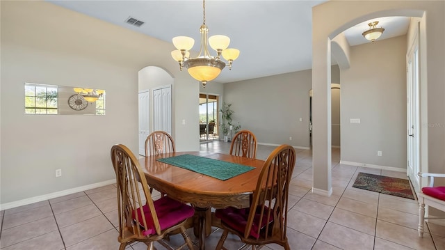 dining room with light tile patterned floors, visible vents, arched walkways, and baseboards