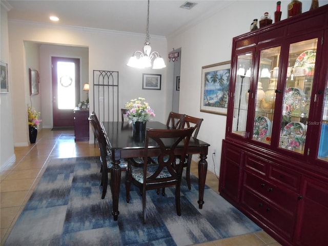 tiled dining room with an inviting chandelier, crown molding, baseboards, and visible vents