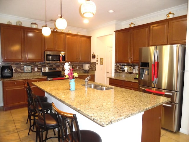 kitchen featuring a sink, backsplash, ornamental molding, appliances with stainless steel finishes, and a kitchen island with sink