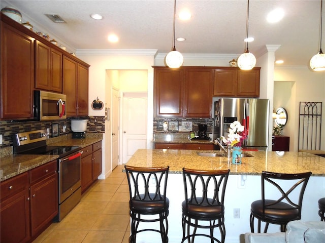 kitchen with light tile patterned floors, a sink, appliances with stainless steel finishes, a kitchen breakfast bar, and decorative light fixtures