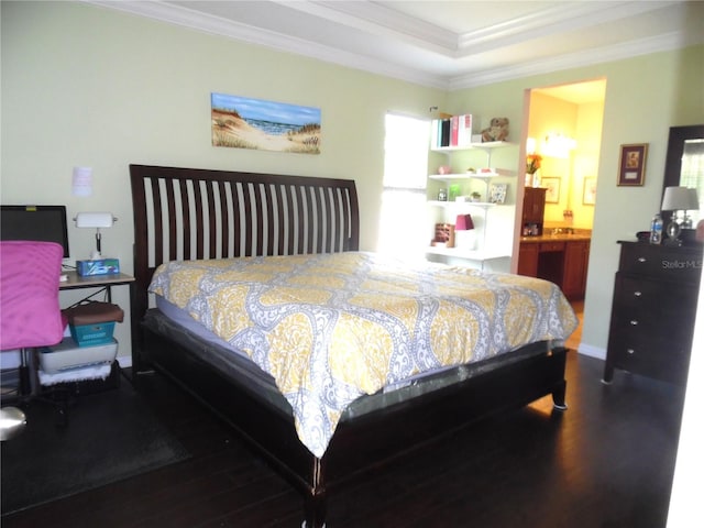 bedroom with baseboards, ensuite bath, wood finished floors, and crown molding