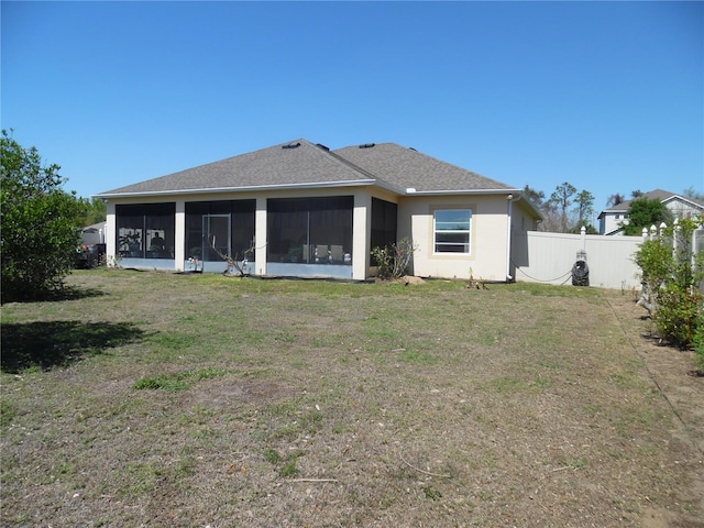 back of house with stucco siding, a lawn, a sunroom, fence, and a shingled roof