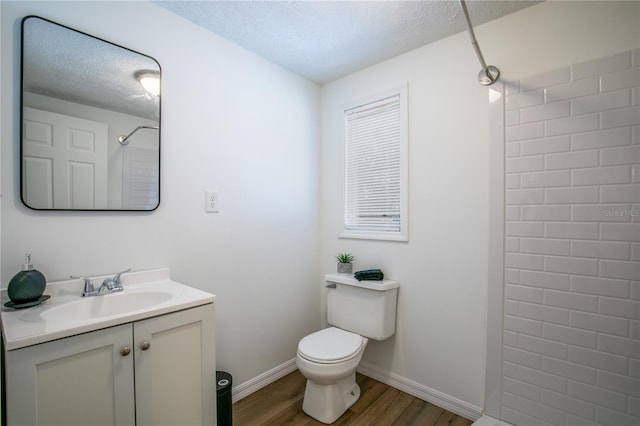 full bath with toilet, a textured ceiling, wood finished floors, walk in shower, and vanity