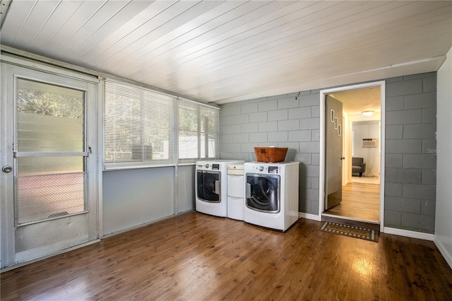 laundry area with baseboards, hardwood / wood-style floors, concrete block wall, and washer and clothes dryer