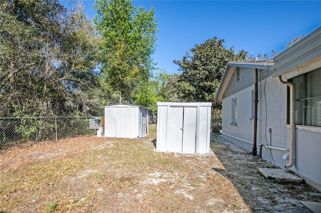 view of yard featuring an outdoor structure, a storage unit, and fence