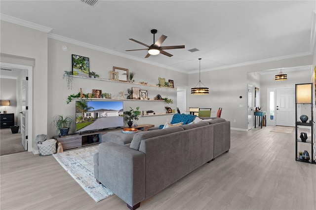 living area featuring a ceiling fan, crown molding, light wood-style floors, and baseboards