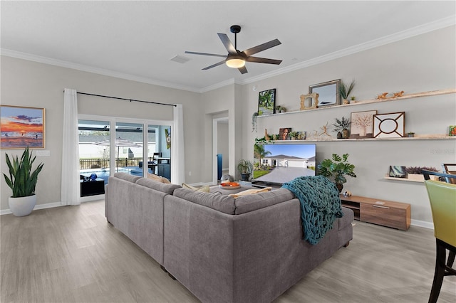 living area with light wood-type flooring, visible vents, ornamental molding, a ceiling fan, and baseboards