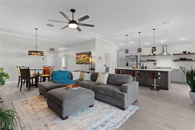 living area featuring visible vents, ornamental molding, and a ceiling fan