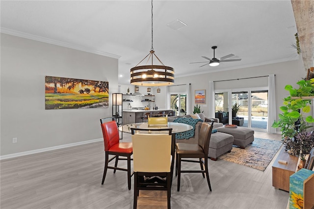 dining area with baseboards, visible vents, light wood-style flooring, crown molding, and ceiling fan with notable chandelier