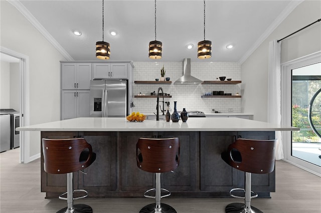 bar featuring ornamental molding, tasteful backsplash, washing machine and dryer, stainless steel fridge, and wall chimney exhaust hood