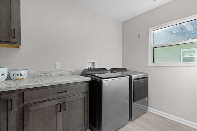 laundry area featuring washer and clothes dryer, cabinet space, light wood finished floors, and baseboards