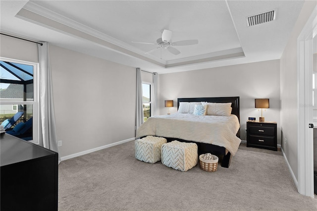 carpeted bedroom with a tray ceiling, baseboards, visible vents, and a ceiling fan