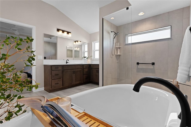 full bath featuring vaulted ceiling, a tile shower, wood finished floors, a soaking tub, and vanity