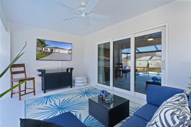 living area with a ceiling fan and a textured wall