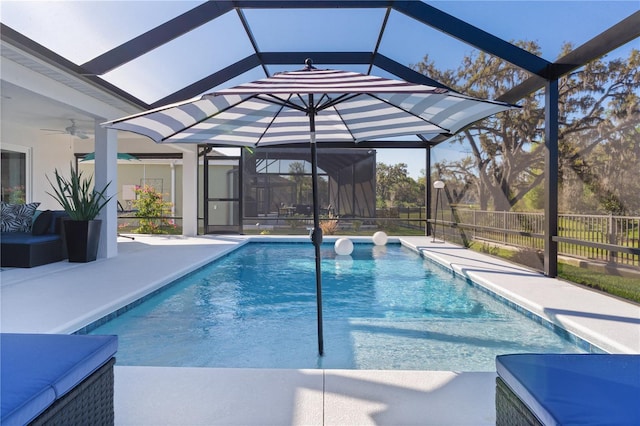 view of swimming pool with glass enclosure, a patio, a fenced in pool, and a ceiling fan