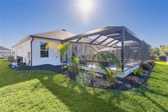 back of house with stucco siding, central air condition unit, a lawn, and a lanai