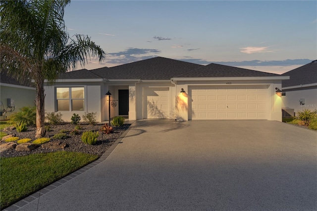 single story home with stucco siding, roof with shingles, concrete driveway, and an attached garage