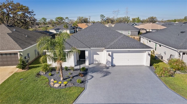 view of front of property with a garage, a front yard, driveway, and a shingled roof