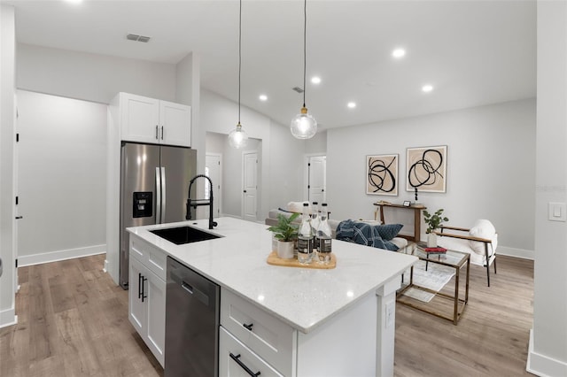 12871 SW 85th Pl, Dunnellon, FL 34432 - kitchen with stainless steel appliances, a sink, white cabinetry, a kitchen island with sink, and light wood-style flooring