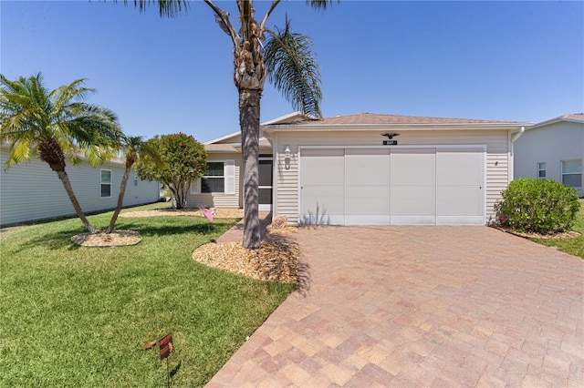 single story home featuring decorative driveway, a front lawn, and an attached garage