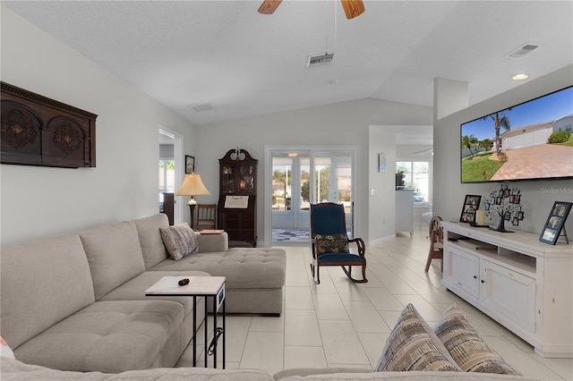 living area with light tile patterned floors, visible vents, lofted ceiling, and a ceiling fan