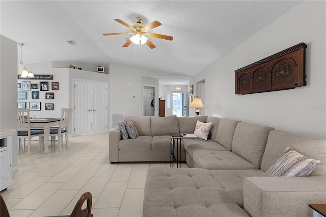 living room featuring vaulted ceiling, ceiling fan with notable chandelier, visible vents, and a textured ceiling