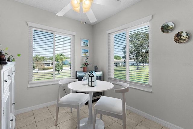 dining area with light tile patterned floors, baseboards, and a ceiling fan