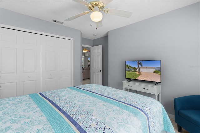 bedroom with a closet, a textured ceiling, visible vents, and a ceiling fan