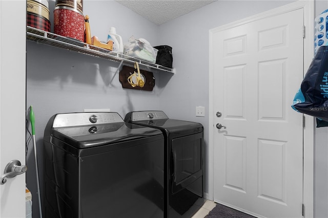 clothes washing area featuring tile patterned flooring, laundry area, independent washer and dryer, and a textured ceiling