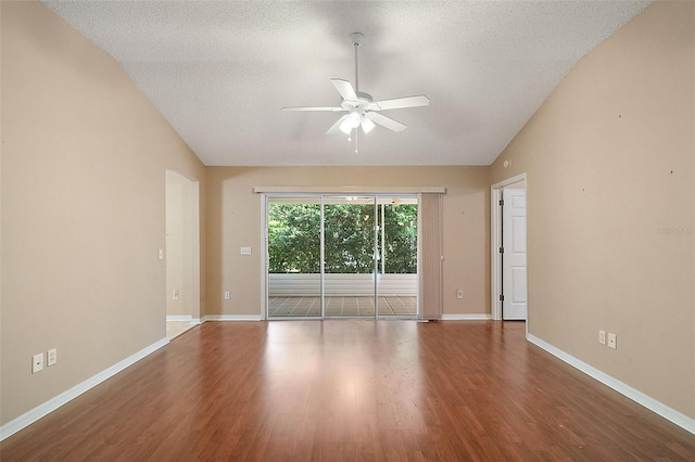 empty room with a textured ceiling, a ceiling fan, lofted ceiling, and wood finished floors