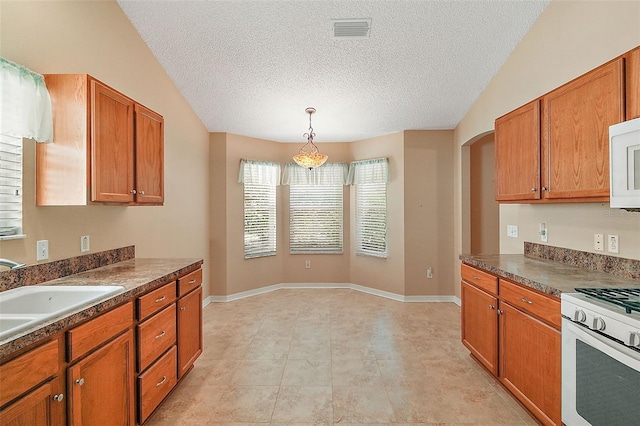 kitchen with visible vents, brown cabinets, a sink, dark countertops, and white appliances