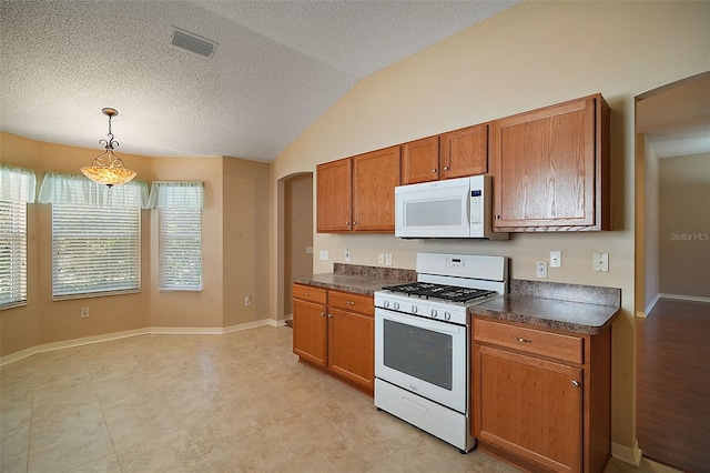 kitchen with visible vents, white appliances, arched walkways, and dark countertops