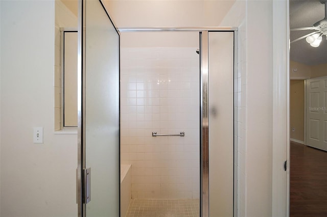 bathroom with wood finished floors, a stall shower, and ceiling fan