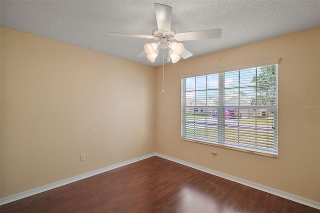 spare room with dark wood-style floors, a textured ceiling, baseboards, and a ceiling fan