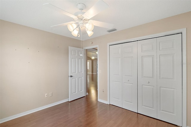 unfurnished bedroom featuring visible vents, a ceiling fan, wood finished floors, a closet, and baseboards