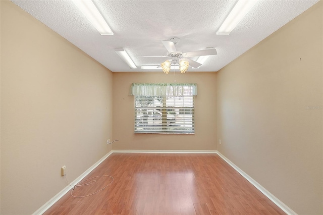 empty room featuring a textured ceiling, baseboards, a ceiling fan, and wood finished floors