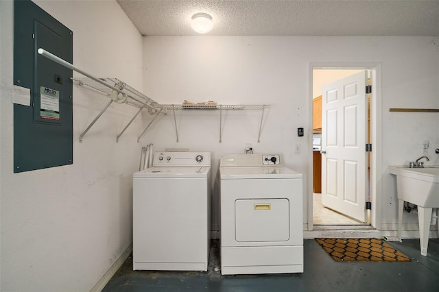 laundry room with electric panel, a textured ceiling, separate washer and dryer, baseboards, and laundry area