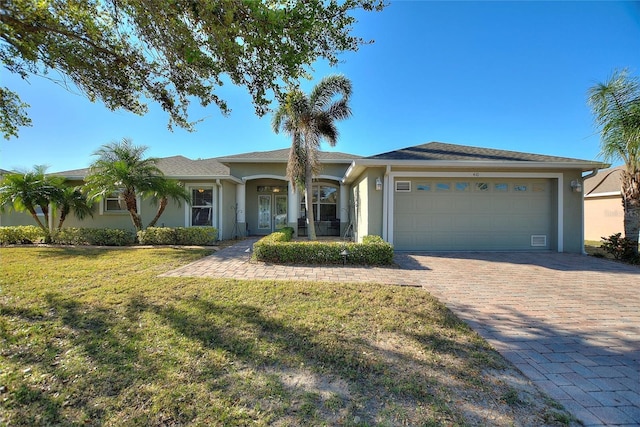 single story home featuring decorative driveway, a front lawn, an attached garage, and stucco siding