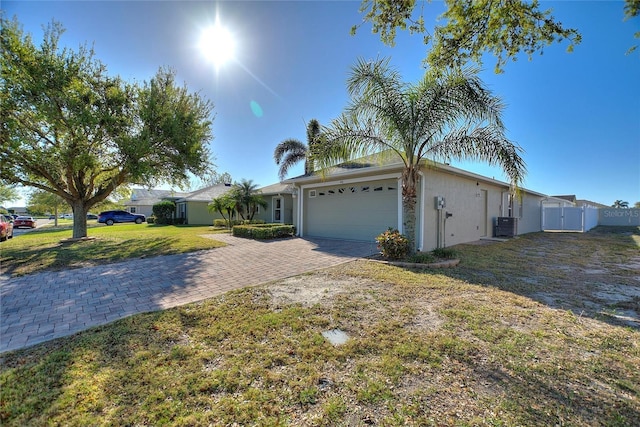 view of front facade with a front lawn, fence, stucco siding, decorative driveway, and a garage