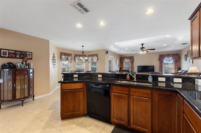 kitchen featuring visible vents, a tray ceiling, a sink, black dishwasher, and ceiling fan with notable chandelier