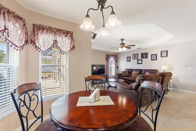 dining area with baseboards, a raised ceiling, light tile patterned flooring, and a ceiling fan