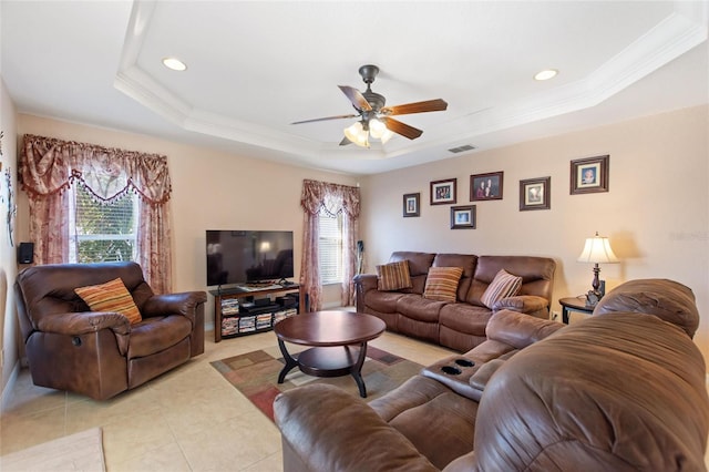 living area featuring a tray ceiling, ceiling fan, light tile patterned flooring, and ornamental molding