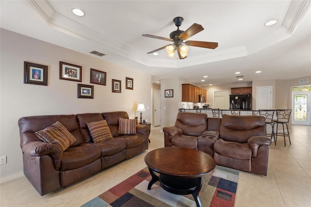 living area with visible vents, a raised ceiling, a ceiling fan, and ornamental molding