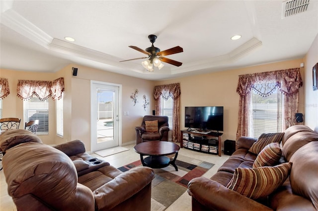 living room featuring visible vents, ceiling fan, a tray ceiling, and ornamental molding