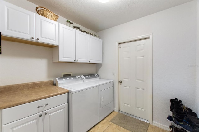 laundry room featuring washer and clothes dryer, light tile patterned floors, cabinet space, and a textured ceiling