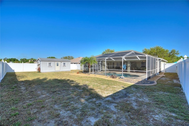 view of yard featuring glass enclosure, an outdoor structure, a fenced backyard, and a fenced in pool