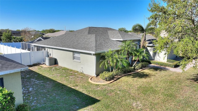 view of property exterior with cooling unit, a yard, roof with shingles, and stucco siding