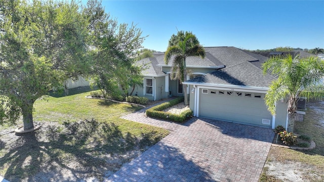 view of front of home featuring stucco siding, decorative driveway, roof with shingles, a front yard, and an attached garage