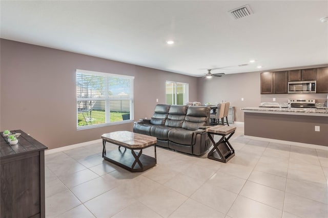 living area featuring a ceiling fan, light tile patterned floors, baseboards, and visible vents