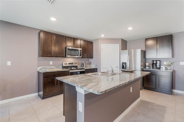 kitchen with light stone counters, dark brown cabinets, appliances with stainless steel finishes, and a sink
